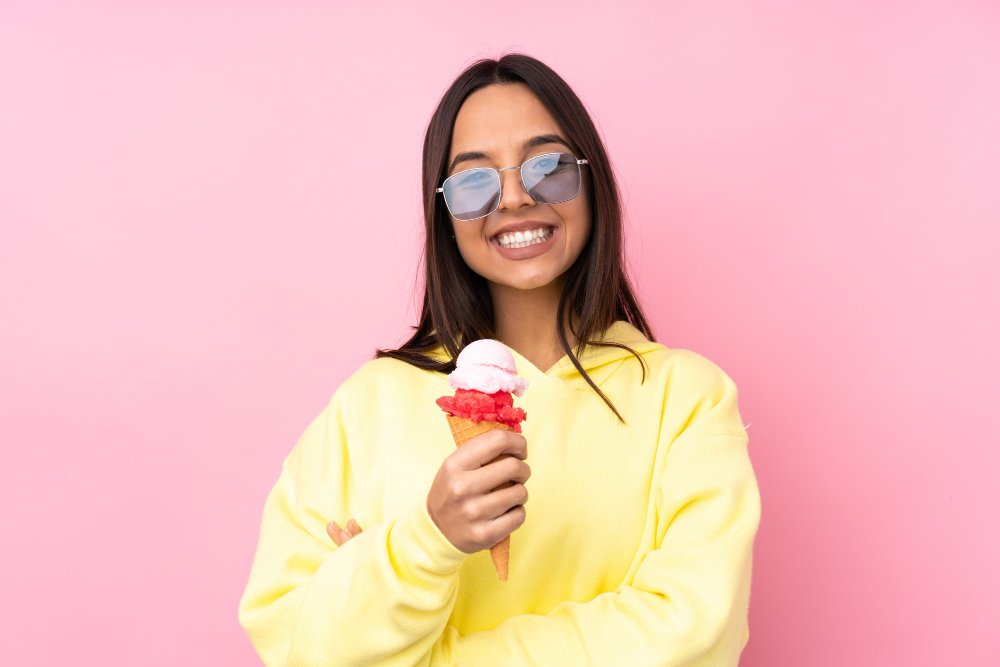 young-brunette-woman-holding-cornet-ice-cream-isolated-pink-looking-up-while-smiling
